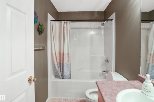 Bathroom featuring a white shower-over-tub unit, a toilet, and a vanity with an integrated sink - 396 Kananaskis Way, Devon, AB - Indoor Photo Showing Bathroom