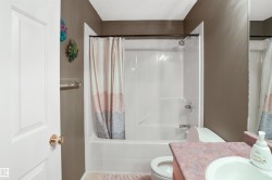 Bathroom featuring a white shower-over-tub unit, a toilet, and a vanity with an integrated sink - 