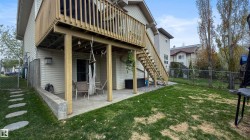 Elevated wood deck with stairs, concrete patio, concrete retaining wall, and a chain-link fence - 