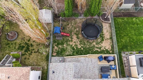 Expansive backyard featuring a multi-level wood deck, mature trees, a storage shed, and a stone-lined fire pit area - 396 Kananaskis Way, Devon, AB - Outdoor
