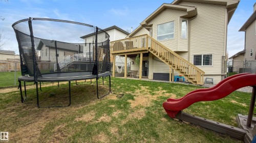 Rear exterior featuring a spacious wooden deck with full staircase access to the backyard - 396 Kananaskis Way, Devon, AB - Outdoor With Deck Patio Veranda
