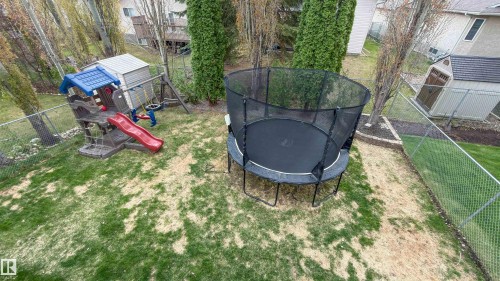 Expansive backyard featuring a chain-link fence, mature trees, and a storage shed - 396 Kananaskis Way, Devon, AB - Outdoor
