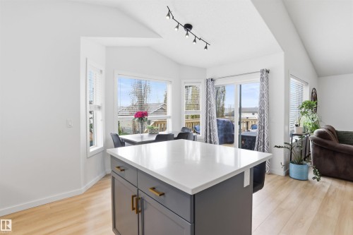 Open-concept kitchen and dining area featuring a central island with a white countertop and dark grey cabinetry with brass hardware - 396 Kananaskis Way, Devon, AB - Indoor