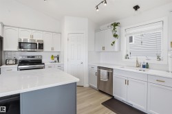 Bright kitchen featuring white cabinetry, light countertops, wood-finish flooring, a stainless steel range, and a stainless steel microwave - 