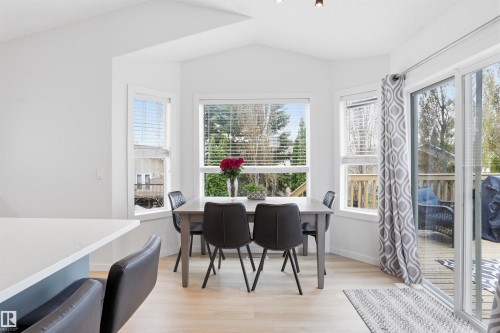 Dining area featuring multiple windows with blinds, a sliding glass door to an outdoor deck, light wood-finish flooring, and white painted walls - 396 Kananaskis Way, Devon, AB - Indoor