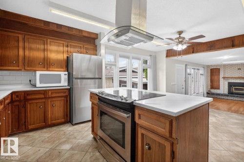 Kitchen featuring wood cabinetry, white countertops, tile flooring, and stainless steel appliances including a refrigerator and range - 8911 84 Avenue, Edmonton, AB - Indoor Photo Showing Kitchen