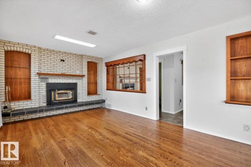 Spacious living area featuring rich wood-finish flooring - 8911 84 Avenue, Edmonton, AB - Indoor Photo Showing Living Room With Fireplace