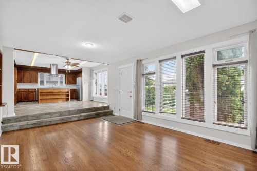 Open-concept living area featuring rich wood-finish flooring and a skylight - 8911 84 Avenue, Edmonton, AB - Indoor