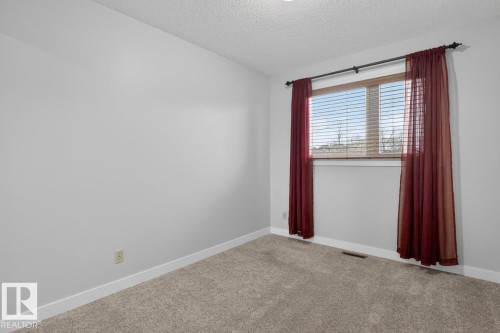 Room featuring light gray walls, white baseboards, and neutral-toned carpeting - 8911 84 Avenue, Edmonton, AB - Indoor