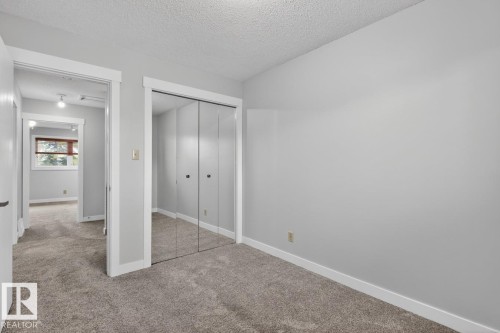 Neutral gray wall paint with white trim, gray carpet flooring, and mirrored closet doors - 8911 84 Avenue, Edmonton, AB - Indoor Photo Showing Other Room