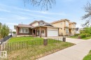 Brick and stucco exterior featuring an integrated garage, covered entry, front lawn, and decorative wrought iron fencing - 8911 84 Avenue, Edmonton, AB  - Outdoor With Facade 