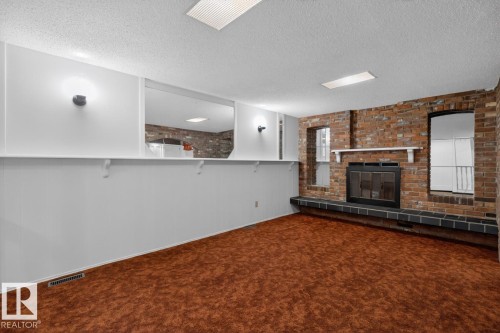 Brick-faced fireplace with a black iron firebox and tile hearth - 8911 84 Avenue, Edmonton, AB - Indoor Photo Showing Other Room With Fireplace