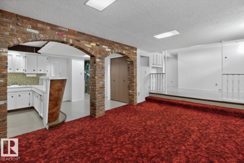 Exposed brick archways define the space, featuring white cabinetry, a built-in wet bar with a wood-finish facade, and recessed ceiling lighting - 8911 84 Avenue, Edmonton, AB - Indoor