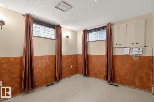 Room featuring two windows with curtain rods and drapes, wall sconces, ceiling-mounted light fixture, and built-in cabinetry - 8911 84 Avenue, Edmonton, AB - Indoor Photo Showing Other Room