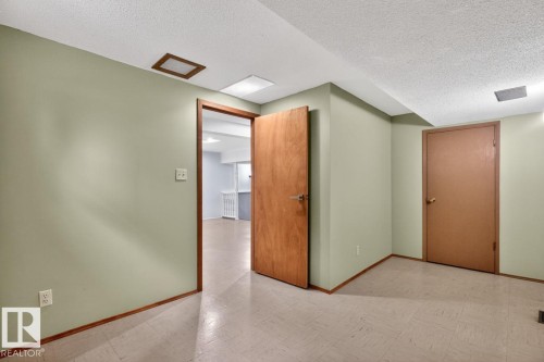 Versatile interior space featuring light green painted walls, wood-finish trim, and neutral-toned flooring - 8911 84 Avenue, Edmonton, AB - Indoor Photo Showing Other Room