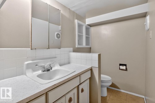 Bathroom vanity with integrated sink, chrome faucet, and white tile backsplash - 8911 84 Avenue, Edmonton, AB - Indoor Photo Showing Bathroom