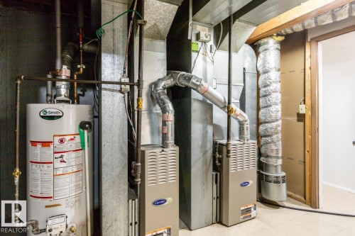 Dedicated utility space featuring a water heater, two furnaces, and extensive ductwork - 8911 84 Avenue, Edmonton, AB - Indoor Photo Showing Basement