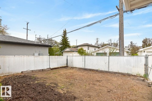 Fenced yard with a chain-link perimeter, featuring a partially tilled area and an adjacent ground space - 8911 84 Avenue, Edmonton, AB - Outdoor
