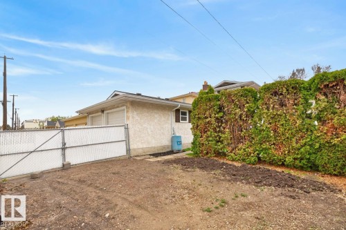 Detached stucco-exterior garage with two garage doors and a chain-link gate - 8911 84 Avenue, Edmonton, AB - Outdoor