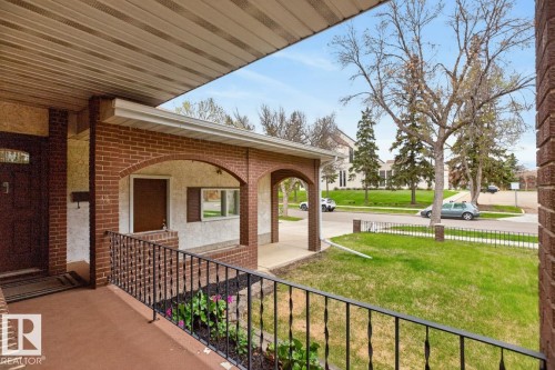 Covered front porch featuring brick arches and a wrought iron railing - 8911 84 Avenue, Edmonton, AB - Outdoor With Exterior