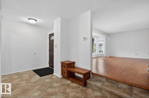Entryway with patterned tile flooring and a dark wood-paneled door - 8911 84 Avenue, Edmonton, AB - Indoor Photo Showing Other Room