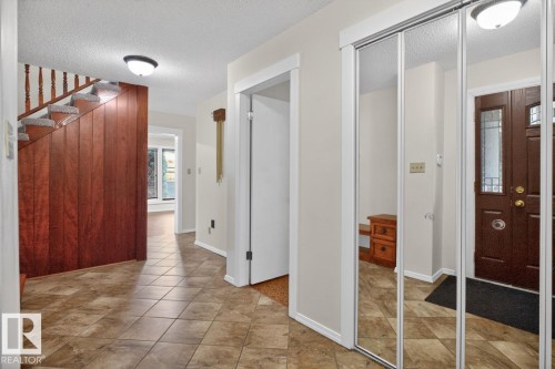 Entryway featuring tiled flooring, a dark wood front door with decorative glass inserts, and mirrored closet doors - 8911 84 Avenue, Edmonton, AB - Indoor Photo Showing Other Room