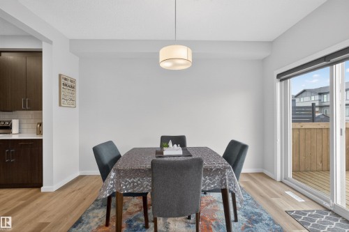 Dining area featuring wood-finish flooring, a contemporary ceiling light fixture, and a sliding glass door providing access to an exterior deck - 332 Juniper Cove, Leduc, AB - Indoor Photo Showing Dining Room