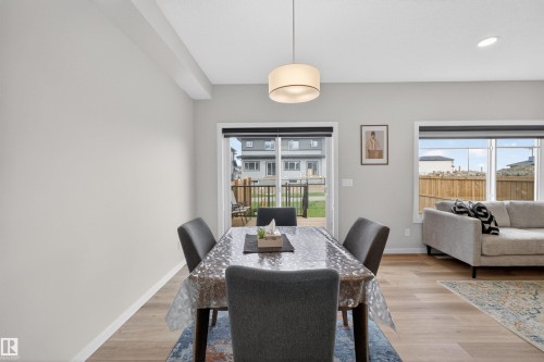 Dining area featuring light wood-finish flooring, a contemporary drum pendant light fixture, and neutral wall tones - 332 Juniper Cove, Leduc, AB - Indoor Photo Showing Dining Room