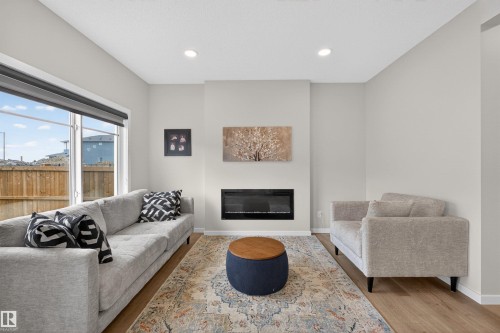 Living area featuring a floor-to-ceiling fireplace with an electric insert, large sliding glass door, recessed lighting, and wood-finish flooring - 332 Juniper Cove, Leduc, AB - Indoor Photo Showing Living Room With Fireplace