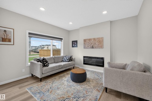 Living area featuring a modern wall-mounted fireplace, a large picture window, and recessed ceiling lighting - 332 Juniper Cove, Leduc, AB - Indoor Photo Showing Living Room With Fireplace