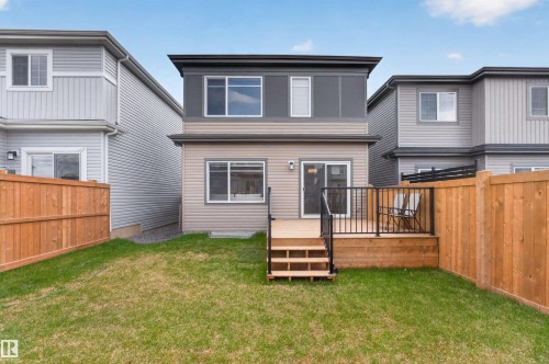 Rear exterior featuring a two-story design with a neutral siding facade and dark trim accents - 332 Juniper Cove, Leduc, AB - Outdoor