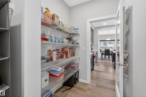 Walk-in pantry with wire shelving, light wood-finish flooring, and a glass-paneled door - 332 Juniper Cove, Leduc, AB - Indoor Photo Showing Other Room