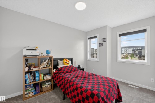 Bright room with light gray walls, textured gray carpeting, two large windows, a flush-mount ceiling light fixture, and white baseboards - 332 Juniper Cove, Leduc, AB - Indoor Photo Showing Bedroom