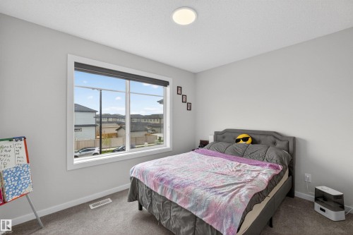 Spacious room featuring a large window with white trim, gray carpet flooring, and light gray painted walls - 332 Juniper Cove, Leduc, AB - Indoor Photo Showing Bedroom