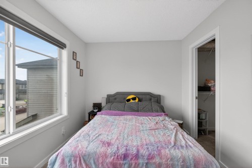 Room featuring a large multi-pane window with a roller shade, light gray wall paint, and a built-in closet with wire shelving - 332 Juniper Cove, Leduc, AB - Indoor Photo Showing Bedroom