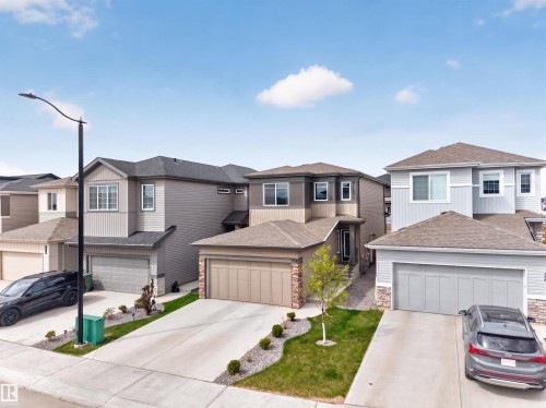 Contemporary two-story residence featuring a two-car garage, stone veneer accents, and a landscaped front yard - 332 Juniper Cove, Leduc, AB - Outdoor With Facade