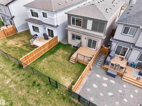 Rear exterior featuring a spacious wood deck with black metal railings, leading to a manicured lawn - 332 Juniper Cove, Leduc, AB - Outdoor With Exterior