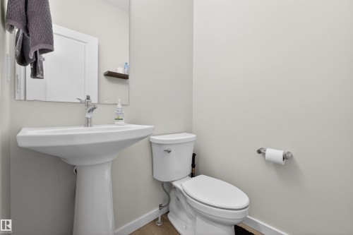 Modern bathroom featuring a white pedestal sink, chrome faucet, and a wall-mounted mirror - 332 Juniper Cove, Leduc, AB - Indoor Photo Showing Bathroom