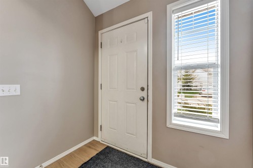 Entryway featuring a paneled door, wood-finish flooring, and light neutral wall tones - 135 150 Edwards Drive, Edmonton, AB - Indoor Photo Showing Other Room