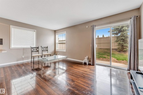 Spacious interior featuring rich wood-finish flooring, neutral wall tones, and multiple windows with blinds - 135 150 Edwards Drive, Edmonton, AB - Indoor