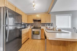 Kitchen featuring light wood cabinetry, stainless steel appliances, a tile backsplash, and light-toned countertops - 