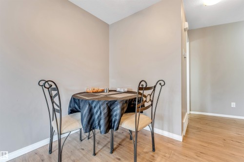 Corner dining area with wood-finish flooring, white baseboards, and neutral wall paint - 135 150 Edwards Drive, Edmonton, AB - Indoor Photo Showing Dining Room