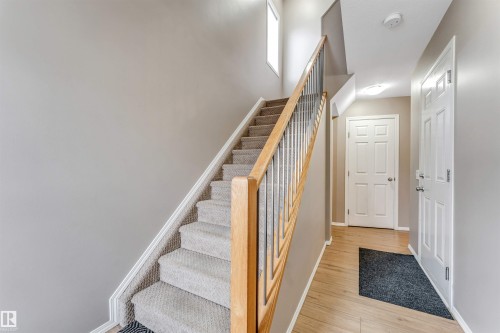 Staircase featuring light wood handrails, metal spindles, and carpeted treads - 135 150 Edwards Drive, Edmonton, AB - Indoor Photo Showing Other Room