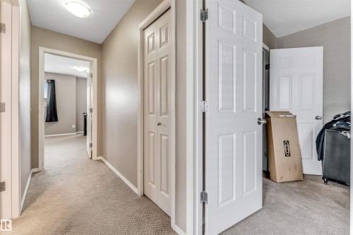 Neutral-toned hallway featuring light beige walls and complementing carpeted flooring - 135 150 Edwards Drive, Edmonton, AB - Indoor Photo Showing Other Room
