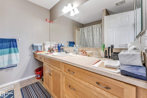 Bathroom vanity featuring a light-toned countertop, integrated sink, and wood-finish cabinetry - 135 150 Edwards Drive, Edmonton, AB - Indoor Photo Showing Bathroom