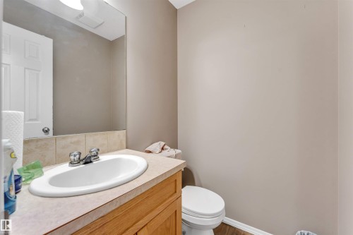 Bathroom vanity featuring a light wood-finish cabinet, integrated sink, and chrome faucet - 135 150 Edwards Drive, Edmonton, AB - Indoor Photo Showing Bathroom