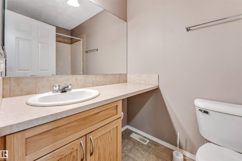 Bathroom vanity with wood-finish cabinetry, a large integrated sink, and a spacious countertop - 135 150 Edwards Drive, Edmonton, AB - Indoor Photo Showing Bathroom