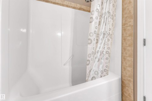 Shower-over-tub combination with white acrylic surround and integrated grab bar - 135 150 Edwards Drive, Edmonton, AB - Indoor Photo Showing Bathroom