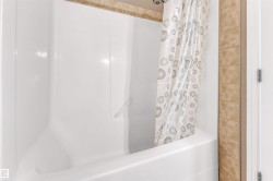 Shower-over-tub combination with white acrylic surround and integrated grab bar - 