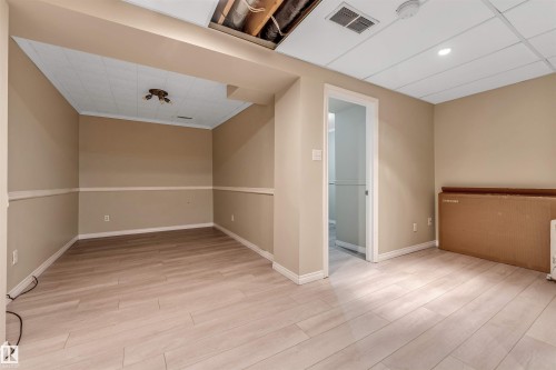 Finished room featuring wood-finish flooring, drop ceiling with recessed lighting, and neutral wall paint with wainscoting - 135 150 Edwards Drive, Edmonton, AB - Indoor Photo Showing Other Room